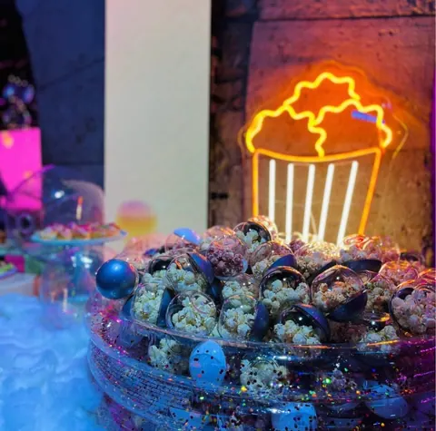 Boules transparentes de popcorn PopComedy sous un néon popcorn, soirée Qonto