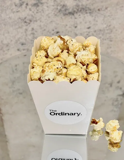 Cornet de popcorn PopComedy au logo The Ordinary