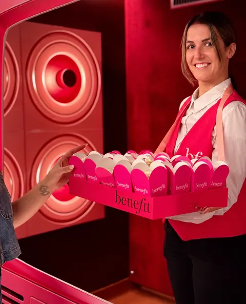 Hôtesse en gilet Benefit tendant un plateau de cornets de popcorn brandés