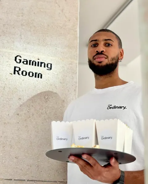 Serveur en t-shirt The Ordinary avec un plateau de cornets de popcorn